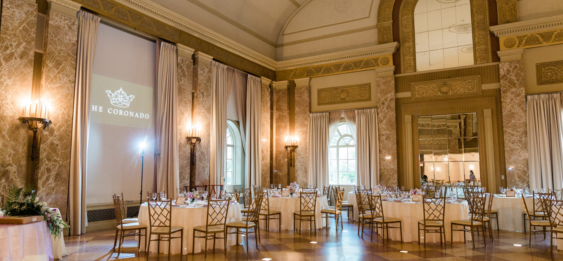 Golden ballroom with high, arched ceilings and tables