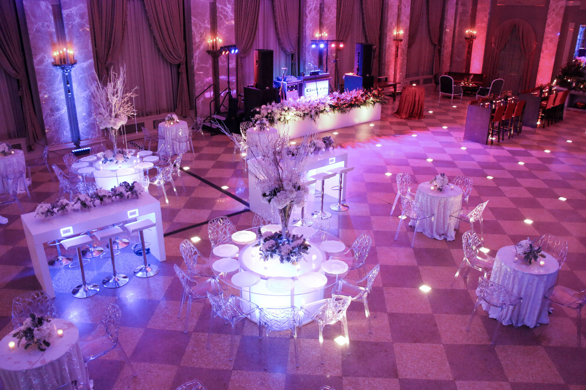 View from above of tables set up for a wedding within a spacious purple-lit ballroom
