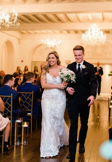 Bride holding pink flowers with groom exiting the center aisle of their ceremony