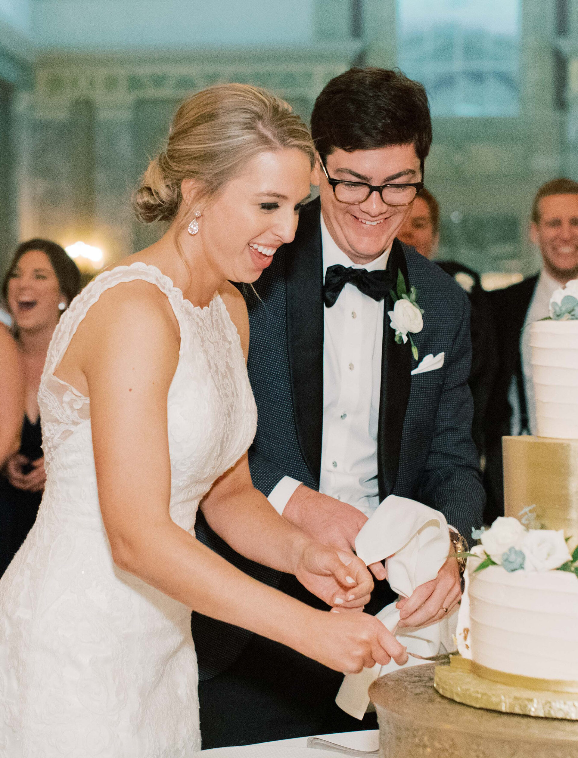 Close up of a woman and man cutting their wedding cake in a soaring ballroom