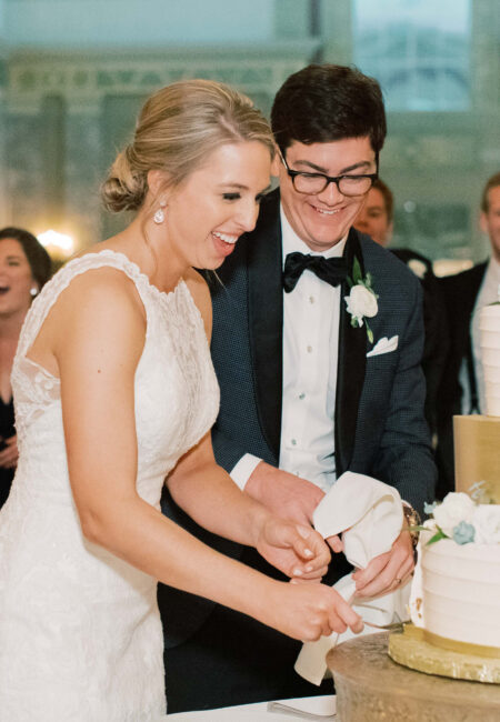 Close up of a woman and man cutting their wedding cake in a soaring ballroom