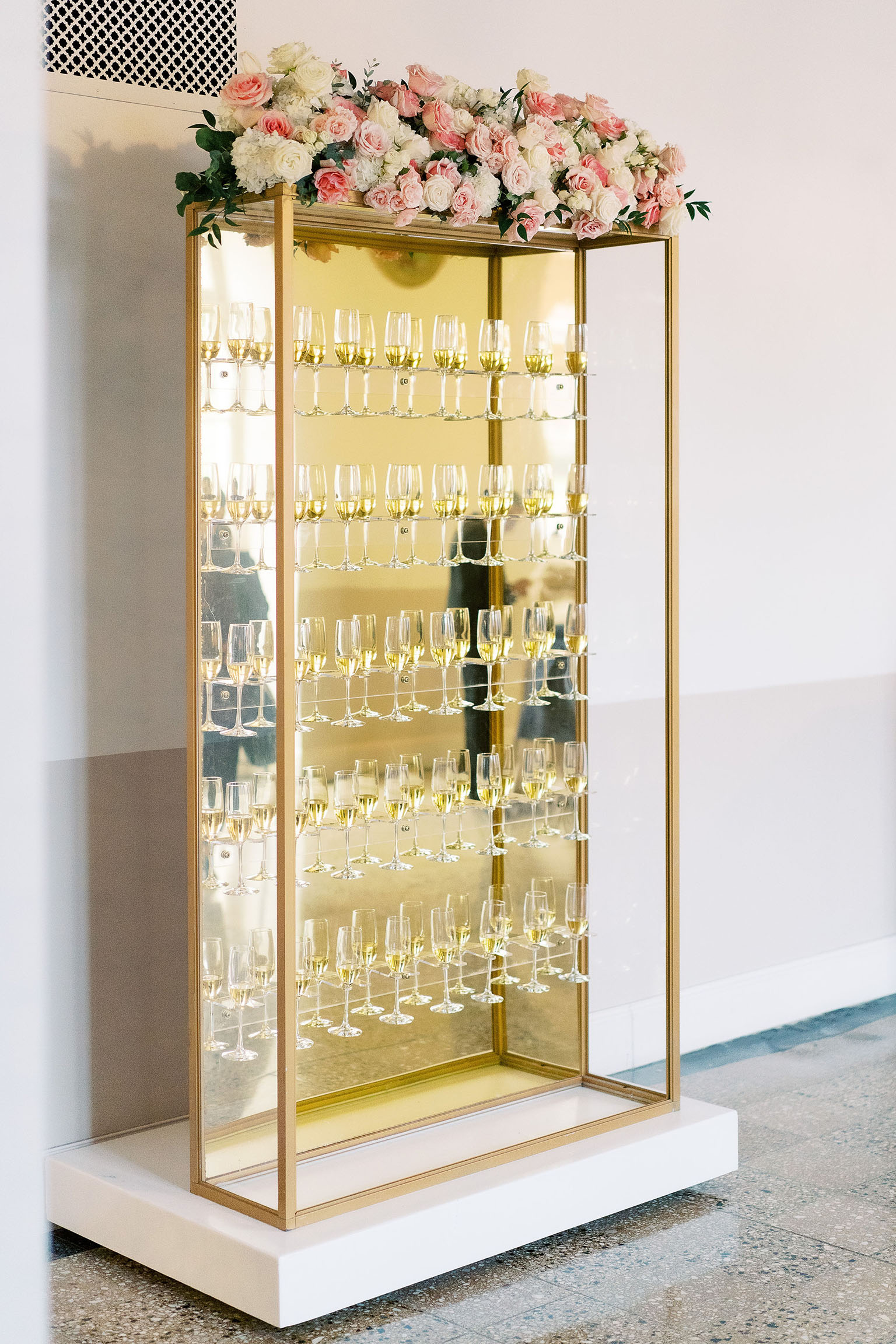 Golden shelving unit holding filled glasses of champagne