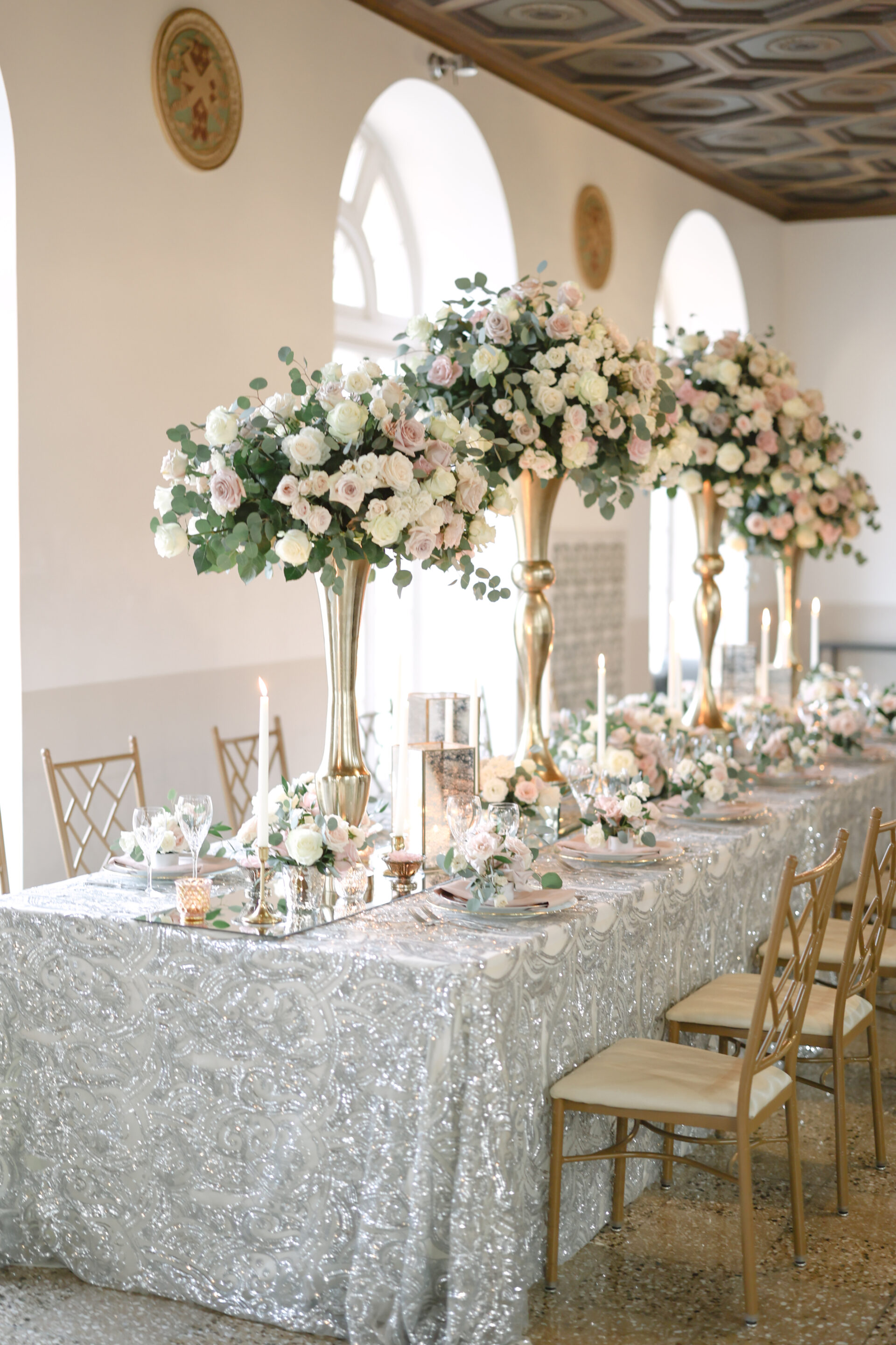 Silver-themed head wedding table with extravagant boquets in gold vases