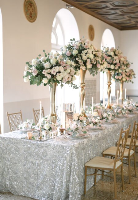 Silver-themed head wedding table with extravagant boquets in gold vases
