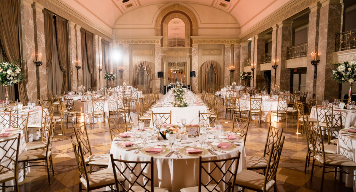 Spacious ballroom with golden marble walls and tables set up for a wedding